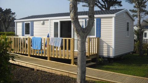 Stacaravan met houten terras en hellingbaan in Flower Camping Cap Finistère, vakantiepark in Bretagne, Frankrijk.
