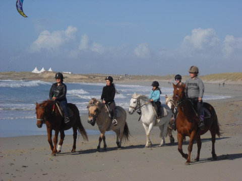 Vijf mensen te paard op het strand bij Flower Camping Cap Finistère, Bretagne, Frankrijk.