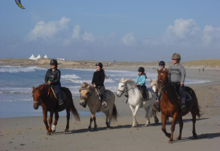 Vijf mensen te paard op het strand bij Flower Camping Cap Finistère, Bretagne, Frankrijk.