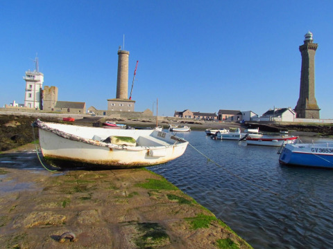 Boten aangemeerd in de haven met vuurtorens op de achtergrond bij Flower Camping Cap Finistère, Bretagne, Frankrijk.