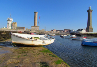 Boten aangemeerd in de haven met vuurtorens op de achtergrond bij Flower Camping Cap Finistère, Bretagne, Frankrijk.
