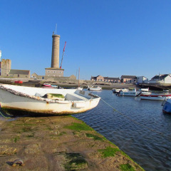 Bateaux amarrés dans le port avec des phares en arrière-plan à Flower Camping Cap Finistère, Bretagne, France.