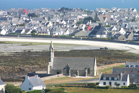 Blick auf Flower Camping Cap Finistère in der Bretagne, Frankreich, mit Kirche und Küstenstadt im Hintergrund.