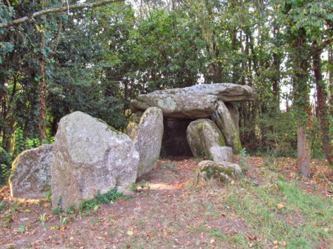 Ancient stone dolmen surrounded by dense trees at Flower Camping Cap Finistère, Brittany, France.