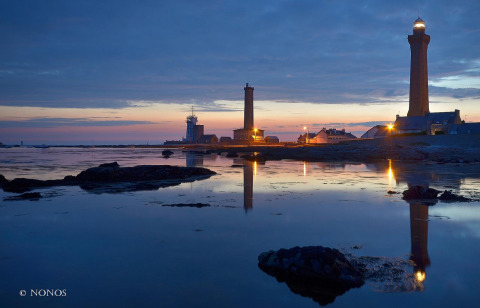 Foto al atardecer de faros y edificios junto al agua en Flower Camping Cap Finistère, Bretaña, Francia.