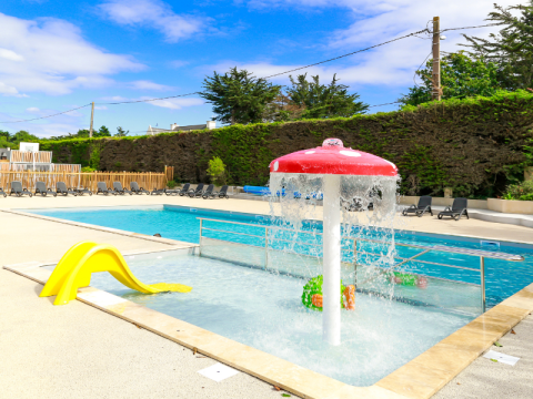 Außenpool mit Kinderbereich, gelber Rutsche und Wasserspiel auf Flower Camping Le Vieux Moulin in der Bretagne, Frankreich.