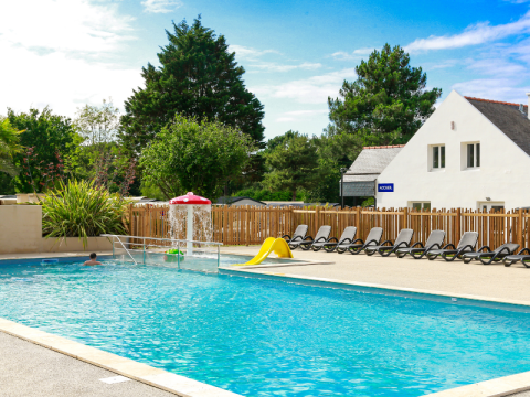 Outdoor swimming pool with loungers, mushroom fountain, and slide at Flower Camping Le Vieux Moulin, Brittany.