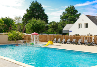 Outdoor swimming pool with loungers, mushroom fountain, and slide at Flower Camping Le Vieux Moulin, Brittany.