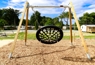 Schaukel mit Netzsitz auf dem Spielplatz von Flower Camping Le Vieux Moulin in der Bretagne, Frankreich.
