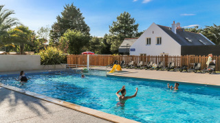 Buitenzwembad met gezinnen die genieten van de zon bij Flower Camping Le Vieux Moulin, Bretagne, Frankrijk.