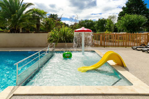 Piscina infantil con tobogán y juegos acuáticos en Flower Camping Le Vieux Moulin, Bretaña, Francia.