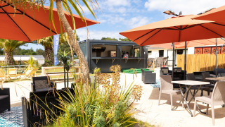 Buitenlounge met parasols en zitplaatsen bij Flower Camping Le Vieux Moulin in Bretagne, Frankrijk.