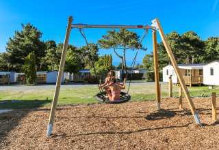Kinder spielen auf einer Schaukel auf dem Spielplatz im Flower Camping Le Vieux Moulin in der Bretagne, Frankreich.