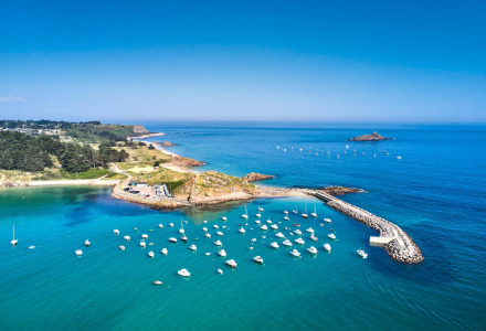 Luchtfoto van de haven van Erquy in Bretagne, Frankrijk, met zeilboten op helderblauw zeewater.