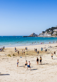 Strand bei Flower Camping Le Vieux Moulin in der Bretagne, Frankreich, mit spielenden und badenden Menschen.