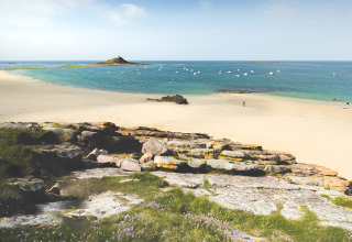 Kustzicht bij Flower Camping Le Vieux Moulin in Bretagne, Frankrijk, met strand, rotsen en zee.