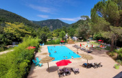 Piscina esterna al Flower Camping Mas de Champel circondata da montagne in Auvergne-Rhône-Alpes, Francia.