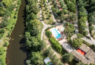 Aerial view of Flower Camping Mas de Champel holiday park featuring a pool, river, and greenery in Auvergne-Rhône-Alpes, France.