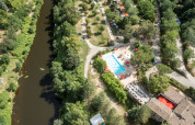 Vista aérea de Flower Camping Mas de Champel con piscina, río y áreas verdes en Auvergne-Rhône-Alpes, Francia.