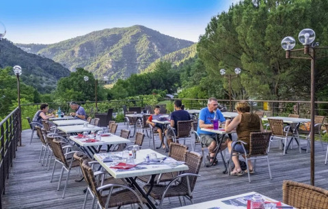 Udendørs restaurantterrasse på Flower Camping Mas de Champel med bjerge i baggrunden i Auvergne-Rhône-Alpes.