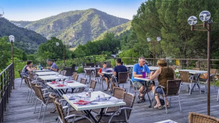 Terrasse de restaurant extérieure au Flower Camping Mas de Champel, offrant une vue sur les montagnes en Auvergne-Rhône-Alpes.