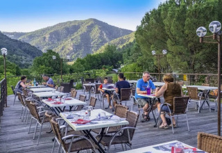 Terrasse de restaurant extérieure au Flower Camping Mas de Champel, offrant une vue sur les montagnes en Auvergne-Rhône-Alpes.