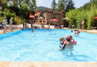 Gezinnen en kinderen vermaken zich in het buitenzwembad op Flower Camping Mas de Champel, Auvergne-Rhône-Alpes.