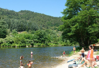 Children and adults enjoy sunny riverside fun at Flower Camping Mas de Champel in Auvergne-Rhône-Alpes, France.