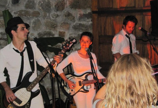 Liveband optræder på Flower Camping Mas de Champel i Auvergne-Rhône-Alpes, Frankrig, med folk foran scenen.