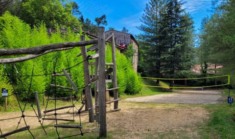Spielplatz und Volleyballfeld bei Flower Camping Mas de Champel im Grünen, Auvergne-Rhône-Alpes, Frankreich.