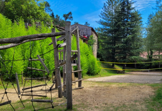 Zona de juegos y cancha de voleibol en Flower Camping Mas de Champel, parque vacacional en Auvernia-Ródano-Alpes, Francia.