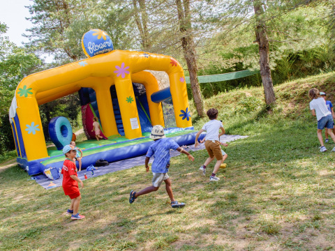 Children playing near a large inflatable bouncy castle at Flower Camping Mas de Champel in France.