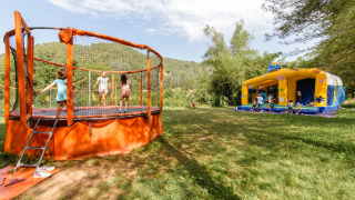 Des enfants jouent sur un trampoline et dans un château gonflable au camping Flower Mas de Champel en France.