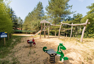 Legeplads med træstrukturer og vippedyr på Flower Camping Mas de Champel i Auvergne-Rhône-Alpes, Frankrig.
