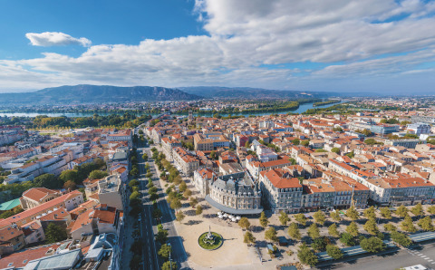 Aerial view of a town near Les Ollières sur Eyrieux, Auvergne-Rhône-Alpes, with river and mountains in the distance.