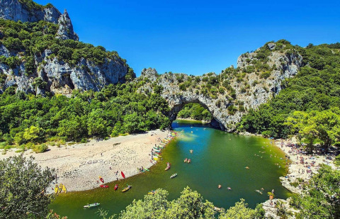 Pont naturel en pierre sur une rivière avec nageurs et kayaks près de Les Ollières sur Eyrieux, Ardèche, France.