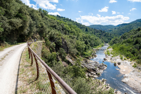 Scenic riverside path with railing at Flower Camping Mas de Champel, Auvergne-Rhône-Alpes, France.