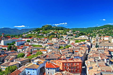 View of Les Ollières sur Eyrieux in Auvergne-Rhône-Alpes, France, with red rooftops and lush green hills.