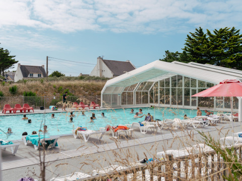 Udendørs swimmingpool med folk, liggestole og overdække på Flower Camping Les Paludiers i Pays de la Loire.