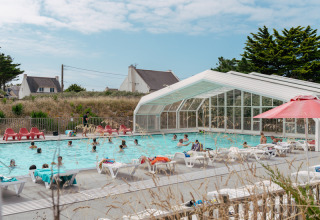 Udendørs swimmingpool med folk, liggestole og overdække på Flower Camping Les Paludiers i Pays de la Loire.