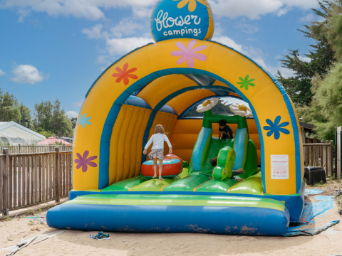 Children playing on a colorful bouncy castle at Flower Camping Les Paludiers in Pays de la Loire, France.
