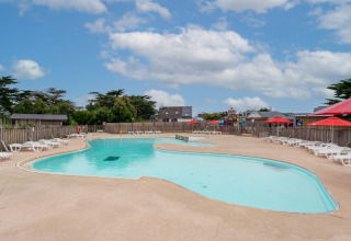 Outdoor swimming pool with white loungers and red umbrellas at Flower Camping Les Paludiers, Pays de la Loire.