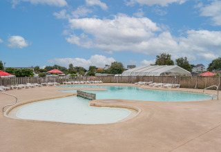Piscina al aire libre con tumbonas y sombrillas en Flower Camping Les Paludiers, Pays de la Loire, Francia.