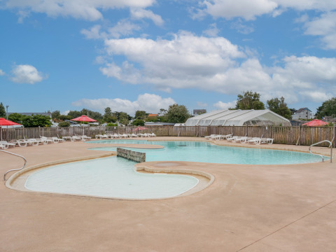 Udendørs swimmingpool med liggestole og parasoller på Flower Camping Les Paludiers i Pays de la Loire, Frankrig.