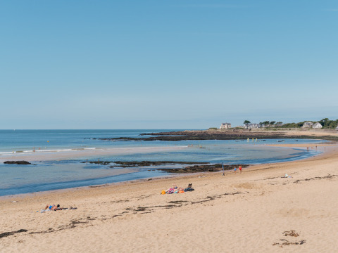 Sandy beach with scattered visitors at Flower Camping Les Paludiers in Pays de la Loire, France on a sunny day.