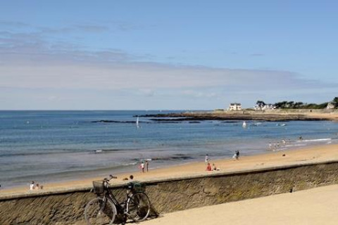 Spiaggia sabbiosa con bicicletta e bagnanti, vista dal Flower Camping Les Paludiers in Pays de la Loire, Francia.