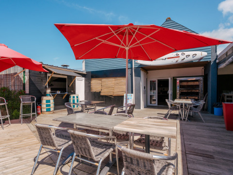 Udendørs terrasse med røde parasoller og caféborde på Flower Camping Les Paludiers i Pays de la Loire.