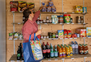 Woman shopping for groceries at Flower Camping Les Paludiers holiday park store in Pays de la Loire, France.