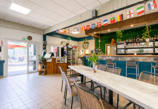 Lichte gemeenschappelijke ruimte met bar en vlaggen bij Flower Camping Les Paludiers in Pays de la Loire, Frankrijk.