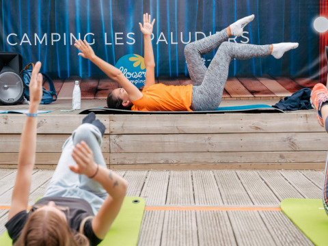 Lezione di ginnastica con istruttrice e partecipanti su tappetini a Flower Camping Les Paludiers in Francia.